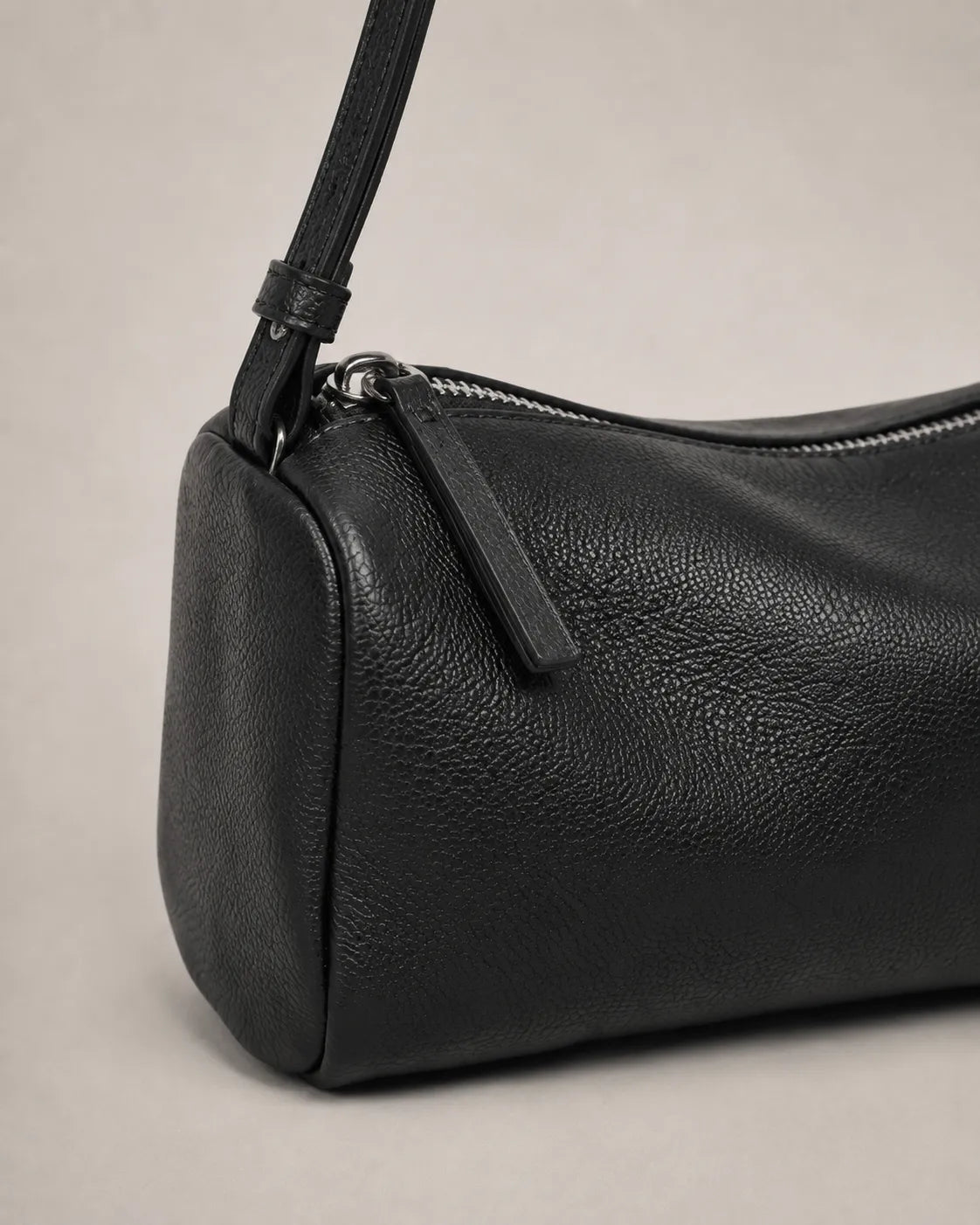 Close-up detail of the Simone genuine leather cylindrical crossbody bag in black showing the leather texture, zip closure and hardware.