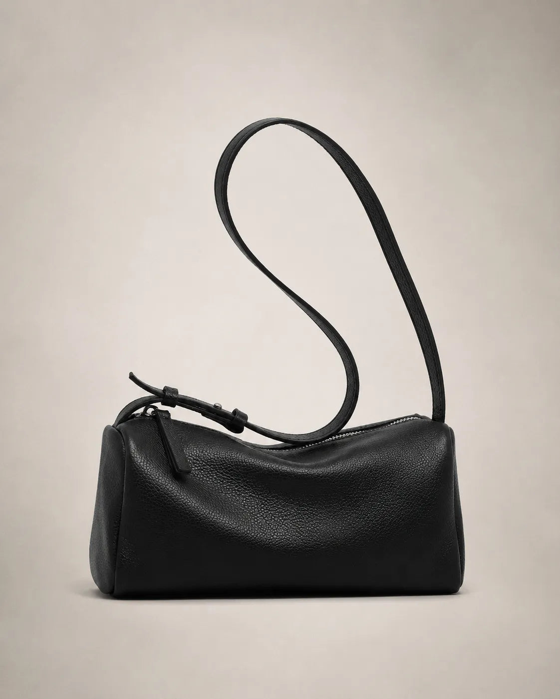 Side view of the Simone genuine leather cylindrical crossbody bag in black showing the barrel silhouette and adjustable strap.