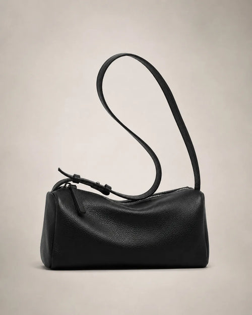 Side view of the Simone genuine leather cylindrical crossbody bag in black showing the barrel silhouette and adjustable strap.