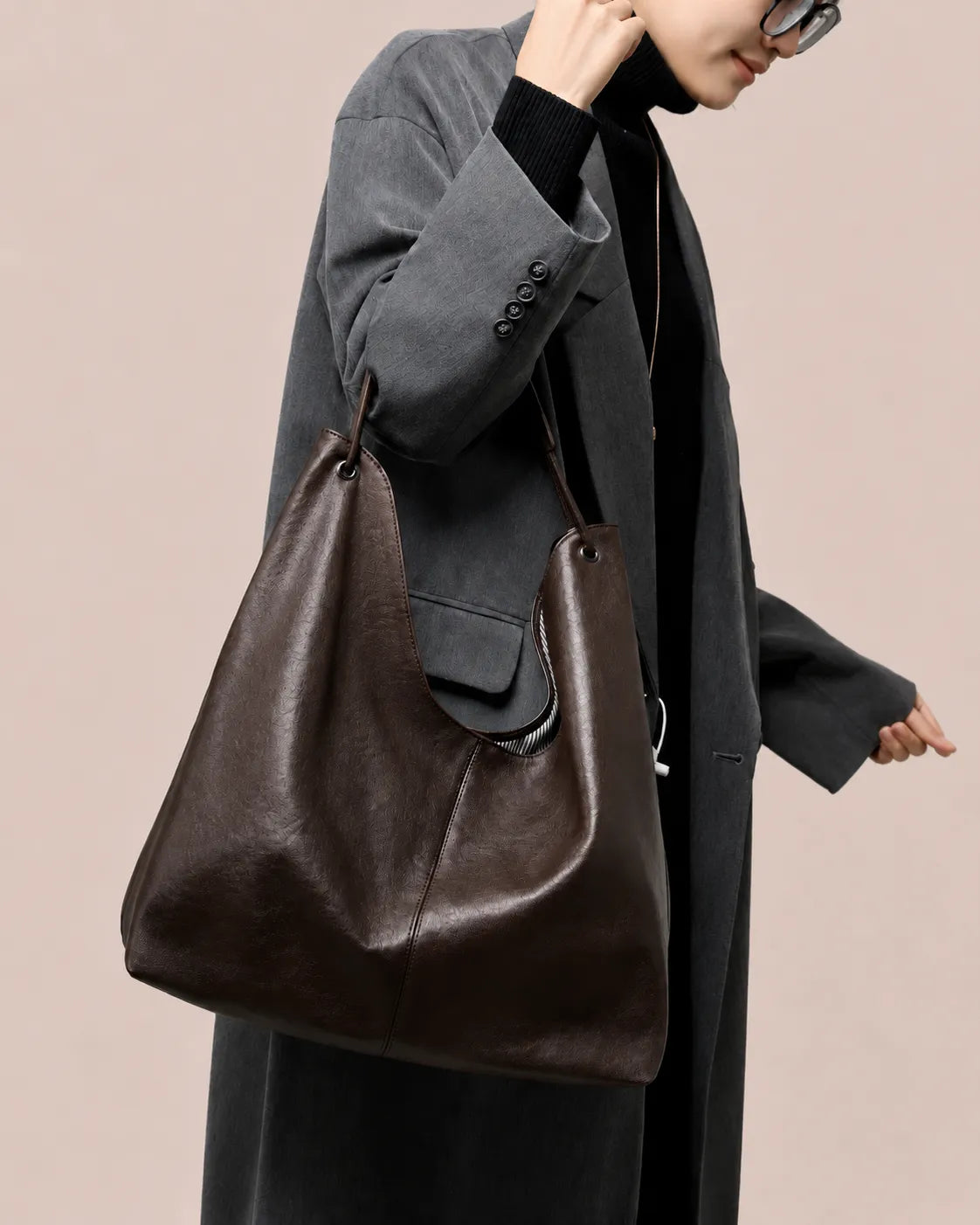 Woman carrying The Colette genuine leather hobo tote bag in Dark Chocolate on the shoulder, showcasing its soft silhouette, spacious design and timeless everyday elegance by Malena London.