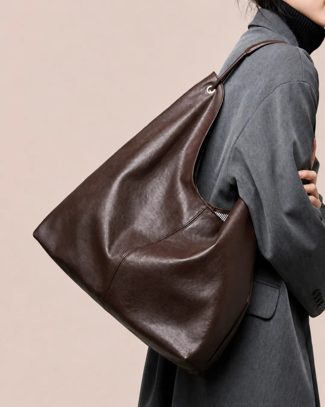 Side view of The Colette genuine leather hobo tote bag in Dark Chocolate worn on the shoulder, highlighting its relaxed shape, soft leather construction and spacious everyday design.