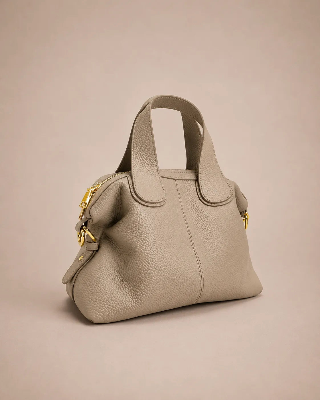 Victoire leather dumpling bag in Elephant Gray genuine leather shown from an angled front perspective, highlighting the soft dumpling silhouette, pebbled leather texture, double handles, adjustable crossbody strap and refined gold-tone hardware.