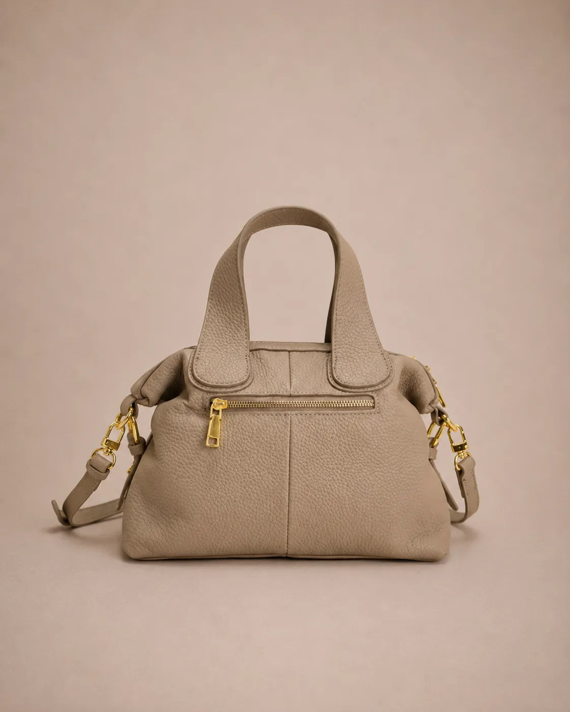Back view of the Victoire leather dumpling bag in Elephant Gray genuine leather showcasing the rear zip pocket, soft structured silhouette, double top handles, adjustable strap and gold-tone hardware on the Malena London studio background.