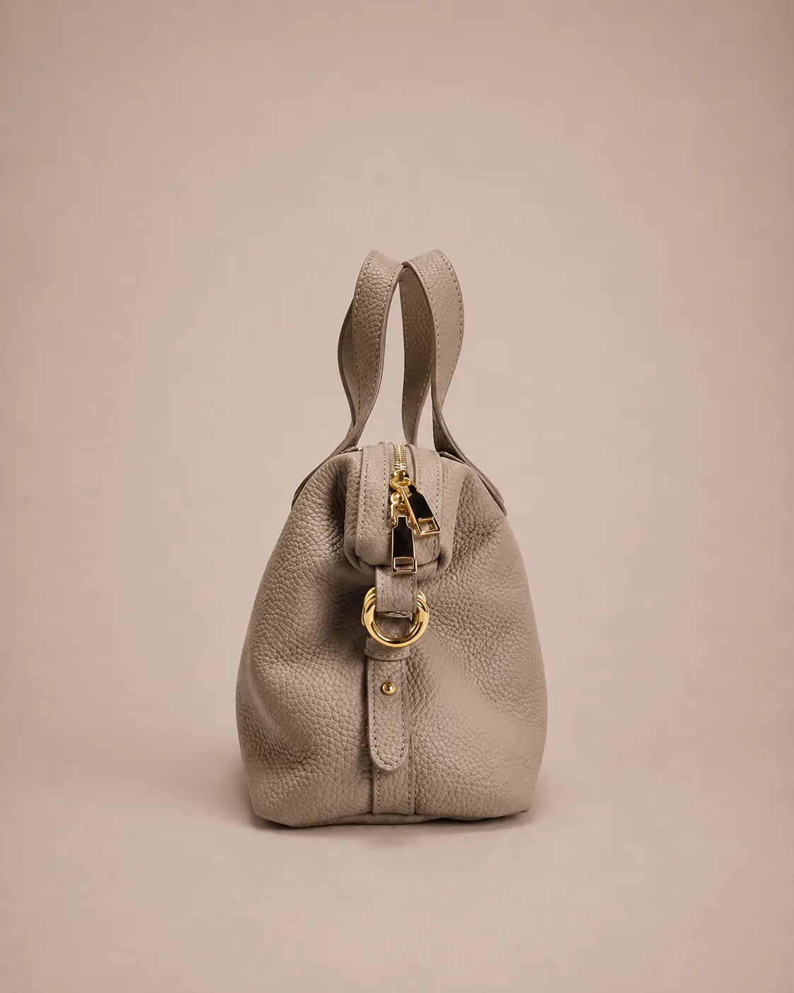 Side view of the Victoire leather dumpling bag in Elephant Gray genuine leather featuring a structured profile, adjustable shoulder strap, premium pebbled leather construction and polished gold-tone hardware.