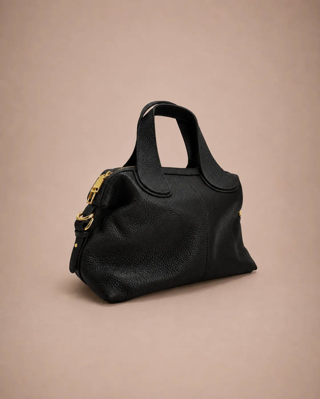 Three quarter front view of the Victoire leather dumpling bag in Black genuine leather featuring a soft structured silhouette, double top handles, premium pebbled leather texture, gold-tone hardware and elegant day-to-evening styling.