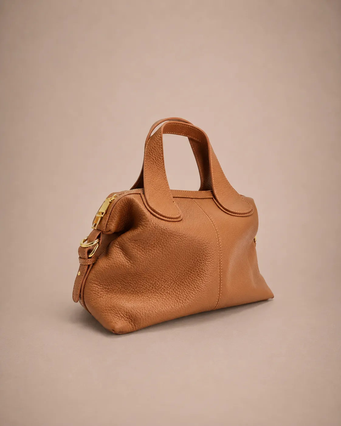 Three quarter front view of the Victoire leather dumpling bag in Brown genuine leather showcasing the soft dumpling silhouette, refined pebbled leather texture, double top handles, gold-tone hardware and versatile everyday elegance.